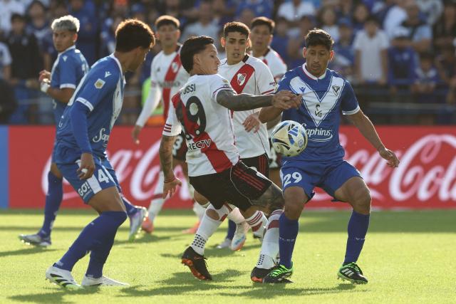 River Plate's forward #19 Sebastian Driussi (C) and Velez Sarsfield's defender #19 Leonel Roldan (R) fight for the ball during the Argentine Professional Football League 2025 Clausura Tournament match between Velez Sarsfield and River Plate at the Jose Amalfitani Stadium in Buenos Aires on November 16, 2025. (Photo by Alejandro PAGNI / AFP)