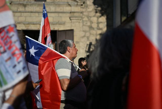 A supporter of Chile's presidential candidate Jeannette Jara, of the Unidad por Chile coalition, waits for the first results during the general election, in Santiago on November 16, 2025. Chileans stood in long lines on Sunday to vote in general elections dominated by far-right calls for an iron fist on crime and mass migrant deportations. (Photo by RODRIGO ARANGUA / AFP)