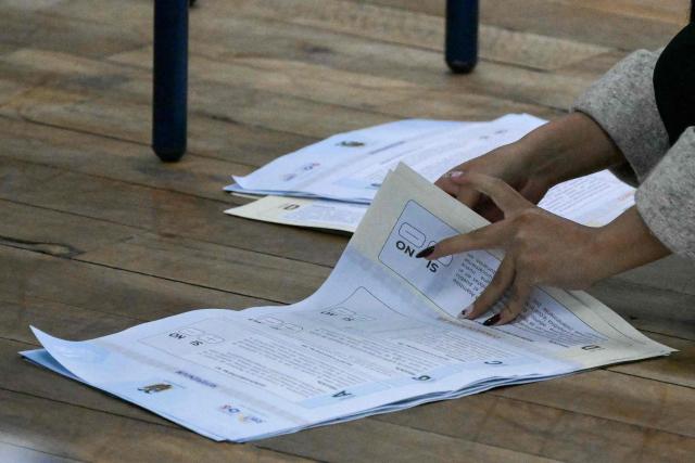 An electoral staffer counts votes during the Ecuador's referendum in Quito on November 16, 2025. Ecuadoreans are voting in a referendum proposed by President Daniel Noboa on whether to allow the return of foreign military bases, draft a new constitution that could expand presidential powers, eliminate public funding for political parties, and reduce the number of lawmakers. (Photo by Rodrigo BUENDIA / AFP)