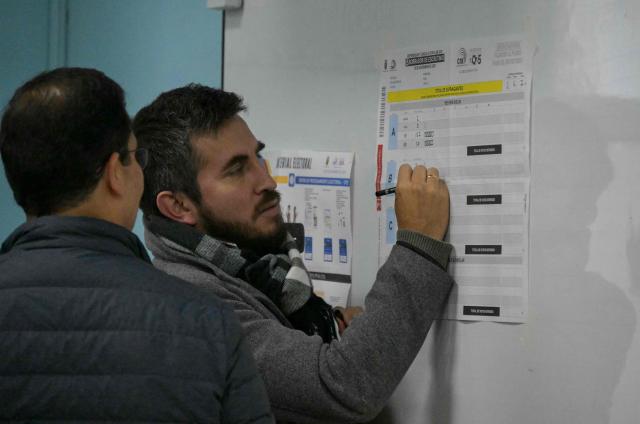 An electoral staffer counts votes during the Ecuador's referendum in Quito on November 16, 2025. Ecuadoreans are voting in a referendum proposed by President Daniel Noboa on whether to allow the return of foreign military bases, draft a new constitution that could expand presidential powers, eliminate public funding for political parties, and reduce the number of lawmakers. (Photo by Rodrigo BUENDIA / AFP)