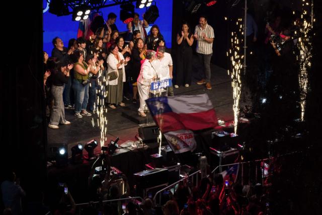 This aerial view shows Chile's presidential candidate Jeannette Jara, of the Unidad por Chile coalition, delivering a speech with her partner Claudio Rodriguez after the first exit poll results of the general election in Santiago on November 16, 2025. (Photo by Javier TORRES / AFP)