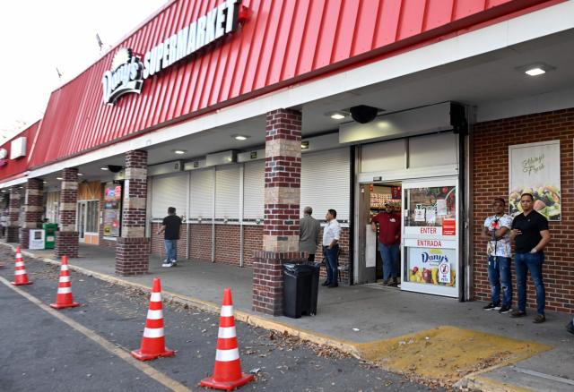 Employees stand alert outside a supermarket as they react to a possible Immigration and Customs Enforcement (ICE) operation in Charlotte, North Carolina, on November 16, 2025. Federal immigration officers began immigration enforcement operations in Charlotte on November 15, they confirmed in a statement. "We are surging DHS law enforcement to Charlotte to ensure Americans are safe and public safety threats are removed," Assistant Homeland Security Secretary Tricia McLaughlin said. US President Donald Trump has made deporting undocumented immigrants a key priority for his second term, after successfully campaigning against an alleged "invasion" by criminals. (Photo by Peter Zay / AFP)