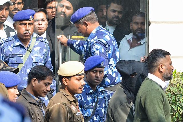 Security personnel escort alleged car blast accused Amir Rashid Ali (2R) with his face covered in black cloth, at the Patiala House Court in New Delhi on November 17, 2025, a day after he was detained. Indian authorities said on November 16, that a deadly car blast near New Delhi's Red Fort earlier this week was an attack carried out by a "suicide bomber", announcing the arrest of an accomplice. (Photo by AFP)