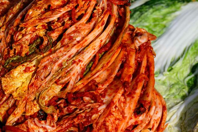 Freshly prepared kimchi is seen next to brined cabbage (R) during a kimchi making festival at Garak Market in Seoul on November 17, 2025. (Photo by ANTHONY WALLACE / AFP)
