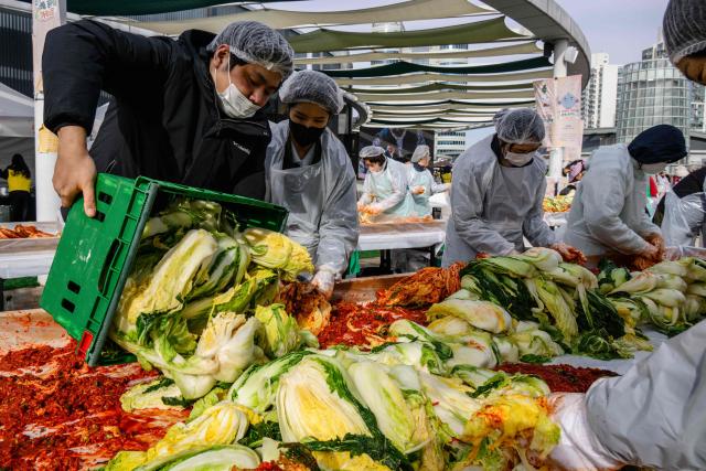 People take part in a kimchi making festival at Garak Market in Seoul on November 17, 2025. (Photo by ANTHONY WALLACE / AFP)