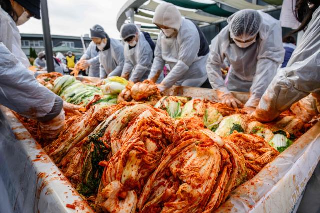 People take part in a kimchi making festival at Garak Market in Seoul on November 17, 2025. (Photo by ANTHONY WALLACE / AFP)