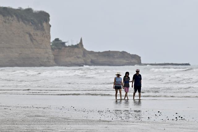 People walk at the beach of Olon, Santa Elena, Ecuador, on November 17, 2025. Ecuadoran voters roundly rejected the return of US military bases to the country in a referendum Sunday, a major political blow to Trump-friendly President Daniel Noboa. (Photo by MARCOS PIN / AFP)