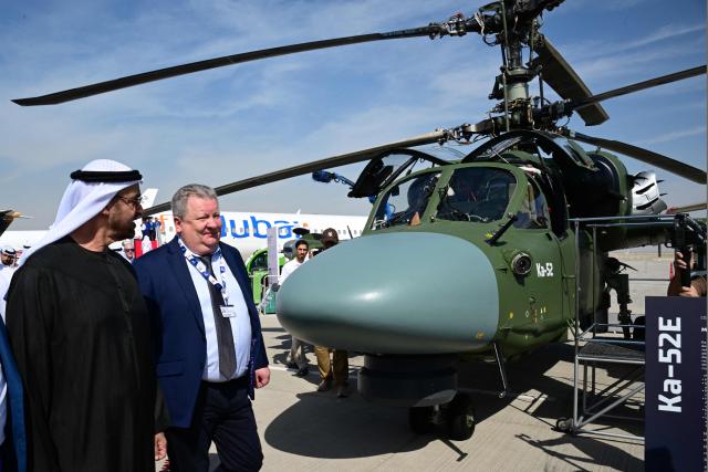 Sheikh Mohamed bin Zayed Al Nahyan, President of the United Arab Emirates and Ruler of the Emirate of Abu Dhabi (L), accompanied by Alexey Lyakin, regional director for JSC Rosoboronexport, walks past a Kamov KA-52E combat helicopter at Al-Maktoum International Airport during the Dubai Airshow 2025 in Dubai on November 17, 2025. (Photo by Giuseppe CACACE / AFP)