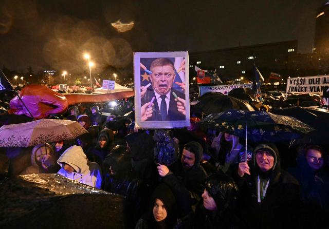 TOPSHOT - A demonstrator holds a picture depicting Prime Minister Robert Fico being scared of chalk referring to the so-called "Chalk Revolution" during a protest against the government of Slovakia's nationalist Kremlin-friendly Prime Minister Robert Fico on November 17, 2025 in Bratislava, Slovakia. Students of a highscool in Poprad had left the room during a speech of Fico on November 14, 2025 at their institution to signal dissent. Czechs and Slovaks rally in both countries, the anniversary of the 1989 Velvet Revolution that toppled communism in former Czechoslovakia, to denounce the leaders they say have betrayed its legacy. On November 17, 1989, communist police brutally crushed a peaceful student march in the centre of Prague, sparking an uprising that toppled the Moscow-steered regime after four decades. Like in the other Soviet-bloc countries at the time, the revolution restored democracy in Czechoslovakia, which then split into the Czech Republic and Slovakia four years later. (Photo by Joe Klamar / AFP)