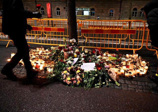 Mourners leave flowers and candles at the scene of an accident where three people died and several were injured when a bus crashed into a bus shelter in Oestermalm, Stockholm, on November 17, 2025. Two Swedish women and a woman from an unnamed European country have been identified as the three people killed when a bus ploughed into a Stockholm bus stop queue last week, police said on November 17. (Photo by Pontus LUNDAHL / TT NEWS AGENCY / AFP) / Sweden OUT