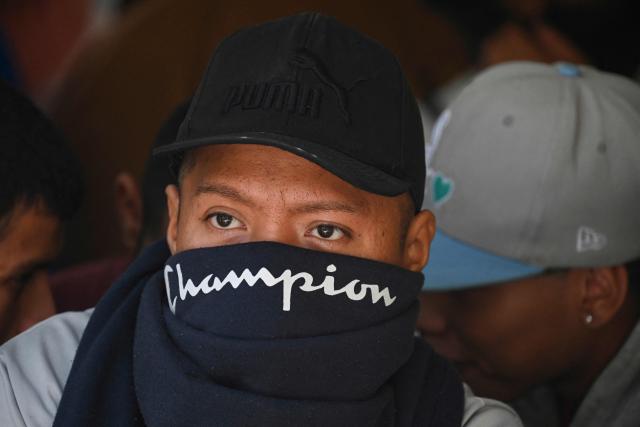 A Mara Salvatrucha gang member with half of his face covered waits during a raid at Pavoncito Prison in Fraijanes, Guatemala on November 17, 2025. The operation is part of measures announced by the new security authorities to regain control of the country's prisons following the October escape of 20 Barrio 18 gang leaders from Fraijanes II Prison, adjacent to Pavoncito. (Photo by Johan ORDONEZ / AFP)