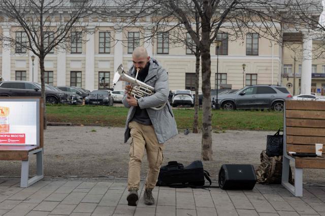 Mark, a 30-year-old Ukrainian soldier, plays the trumpet on the street during his vacation, in Kyiv, on November 17, 2025, amid the Russian invasion of Ukraine. (Photo by Tetiana DZHAFAROVA / AFP)