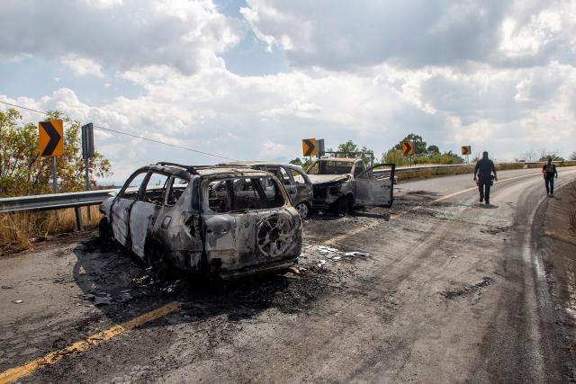 Attorney General's Office of the State of Michoacan (FGE) officers inspect the area where four vehicles were set on fire by alleged members of organized crime on a highway near Quiroga, Michoacan state, Mexico on November 17, 2025. Armed civilians blocked several roads in the western Mexican state of Michoacan on November 17, 2025, in response to an operation against a criminal leader, a week after the government of President Claudia Sheinbaum reinforced the presence of federal forces in the state. (Photo by Enrique CASTRO / AFP)