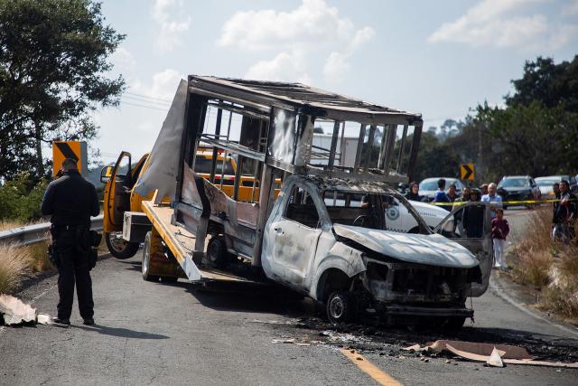 Attorney General's Office of the State of Michoacan (FGE) officers tow one of four vehicles burned by alleged members of organized crime on a highway near Quiroga, Michoacan state, Mexico on November 17, 2025. Armed civilians blocked several roads in the western Mexican state of Michoacan on November 17, 2025, in response to an operation against a criminal leader, a week after the government of President Claudia Sheinbaum reinforced the presence of federal forces in the state. (Photo by Enrique CASTRO / AFP)