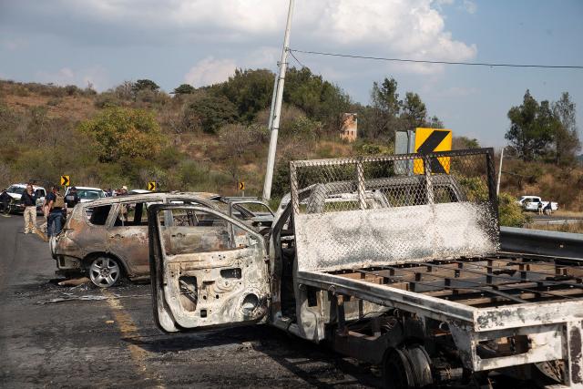 Attorney General's Office of the State of Michoacan (FGE) officers inspect the area where four vehicles were set on fire by alleged members of organized crime on a highway near Quiroga, Michoacan state, Mexico on November 17, 2025. Armed civilians blocked several roads in the western Mexican state of Michoacan on November 17, 2025, in response to an operation against a criminal leader, a week after the government of President Claudia Sheinbaum reinforced the presence of federal forces in the state. (Photo by Enrique CASTRO / AFP)