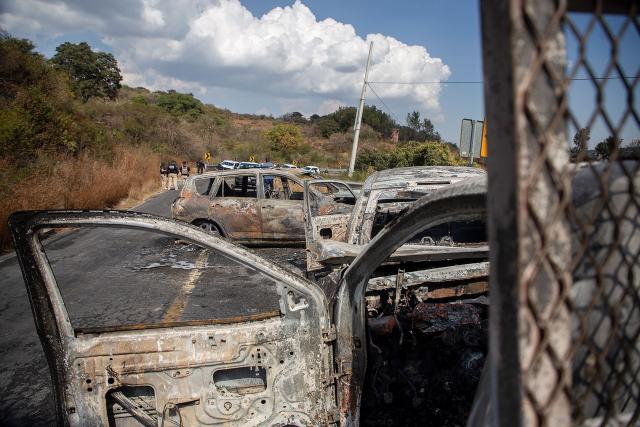 Attorney General's Office of the State of Michoacan (FGE) officers inspect the area where four vehicles were set on fire by alleged members of organized crime on a highway near Quiroga, Michoacan state, Mexico on November 17, 2025. Armed civilians blocked several roads in the western Mexican state of Michoacan on November 17, 2025, in response to an operation against a criminal leader, a week after the government of President Claudia Sheinbaum reinforced the presence of federal forces in the state. (Photo by Enrique CASTRO / AFP)