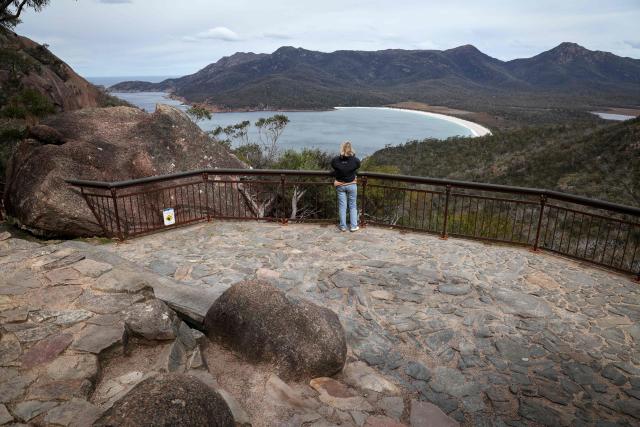 This picture taken on November 5, 2025 shows a tourist at a lookout located above Wineglass Bay at Freycinet Peninsula in Tasmania’s Freycinet National Park. (Photo by DAVID GRAY / AFP)