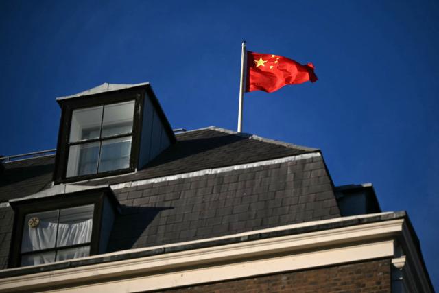 A flag flies atop a pole on the roof of the Embassy of the People's Republic of China in the United Kingdom, on Portland Place in London on November 18, 2025. Britain's domestic intelligence agency MI5 on November 18, warned that China was trying to recruit parliamentarians through spies disguised as headhunters, amid concern over Beijing's activities in the UK. There have been heightened fears about Chinese espionage in the UK after a politically sensitive case against two alleged spies was dropped, and as the government mulls a request from Beijing to build a controversial new embassy building in London. (Photo by JUSTIN TALLIS / AFP)