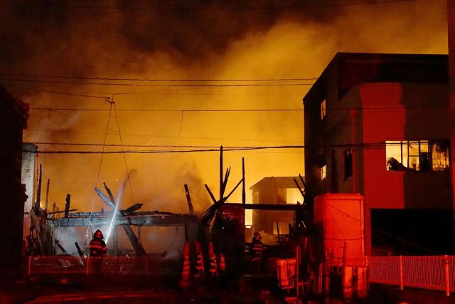 Firefighters work at the scene of a major blaze at a residential area in Saganoseki, Oita City late on November 18, 2025. One person was unaccounted for while 175 others were evacuated as a major fire engulfed a residential area in Japan, the local government said on November 19. (Photo by JIJI Press / AFP) / Japan OUT