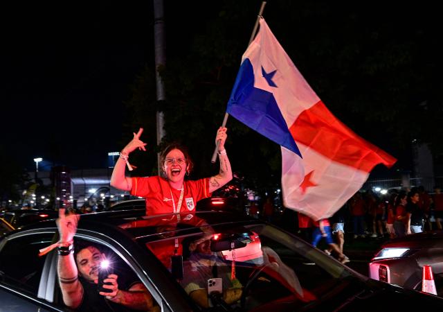A Panamanian woman waves a flag to celebrate after Panama qualified for the 2026 FIFA World Cup in Panama City on November 18, 2025. (Photo by MARTIN BERNETTI / AFP)