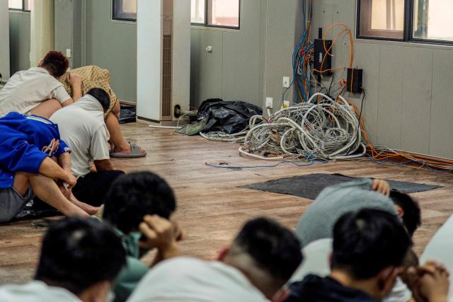 (FILES) Alleged scam centre workers and victims sit next to dismantled IT and electronic appliances during a crackdown operation by the Karen Border Guard Force (BGF) on illicit activity in Shwe Kokko in Myanmar's eastern Myawaddy township on February 18, 2025. Myanmar's military said it raided the internet scam hub of Shwe Kokko on the Thai border, arresting nearly 350 people, part of a highly publicised crackdown against the booming black market compounds. (Photo by AFP)