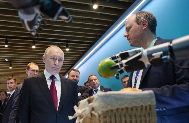 In this pool photograph distributed by the Russian state agency Sputnik, Russia's President Vladimir Putin visits an exhibition of the AI Journey international AI (Artificial intelligence) conference in Moscow on November 19, 2025. Russia's anthropomorphic AI-equipped robot developed by technology company Sber was presented to the Russian leader. (Photo by Vyacheslav PROKOFYEV / POOL / AFP)