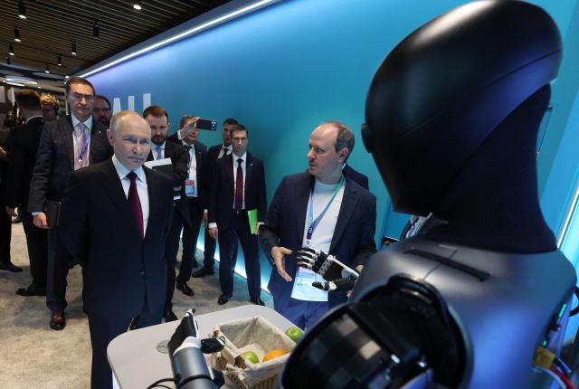 In this pool photograph distributed by the Russian state agency Sputnik, Russia's President Vladimir Putin visits an exhibition of the AI Journey international AI (Artificial intelligence) conference in Moscow on November 19, 2025. Russia's anthropomorphic AI-equipped robot developed by technology company Sber was presented to the Russian leader. (Photo by Vyacheslav PROKOFYEV / POOL / AFP)