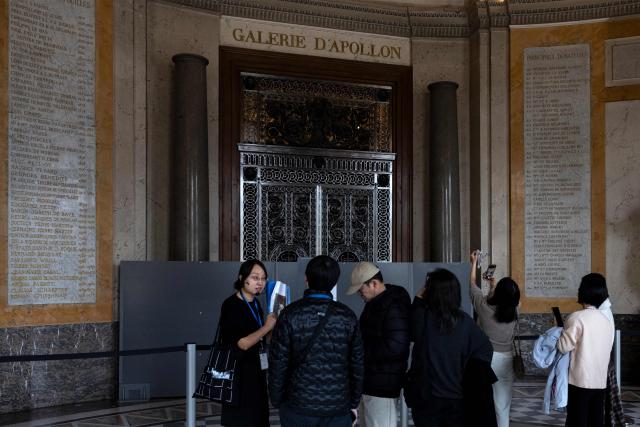 Visitors gather by the closed Apollo Gallery (Galerie d'Apollon) at the Louvre Museum in Paris on November 19, 2025. A four-strong gang raided the Louvre's Apollo Gallery last month with an extendable ladder and power tools in broad daylight, making off with jewellery worth an estimated $102 million in front of startled visitors. (Photo by Sébastien DUPUY / AFP)