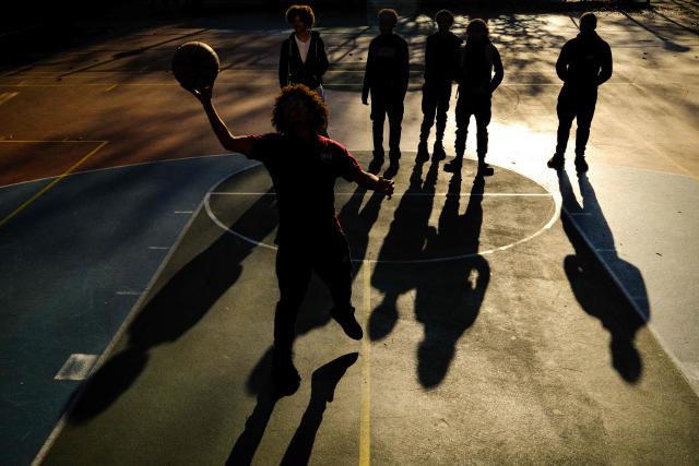 Young boys play basketball on a playground in the Hamilton Heights neighborhood of Manhattan in New York City on November 19, 2025. (Photo by CHARLY TRIBALLEAU / AFP)