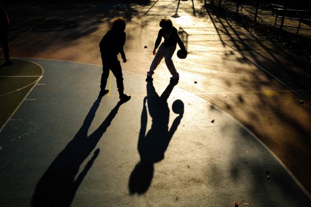 Young boys play basketball on a playground in the Hamilton Heights neighborhood of Manhattan in New York City on November 19, 2025. (Photo by CHARLY TRIBALLEAU / AFP)
