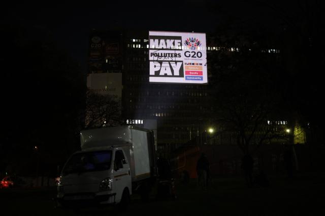 The Glasgow Actions Team project a message onto a building, calling for major polluters, particularly fossil fuel companies, be held financially accountable for environmental damage and made to pay for climate action in Johannesburg on November 19, 2025, ahead of the G20 leaders’ summit. (Photo by EMMANUEL CROSET / AFP)