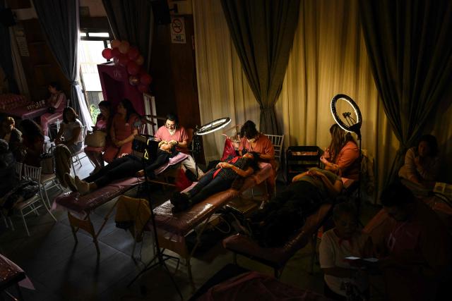 Cancer patients receive care during a free beauty and oncological micropigmentation event called "Delineating Smiles" in the Iztapalapa neighborhood of Mexico City on November 19, 2025. The "Delineating Smiles" event offered therapeutic care to women with cancer from 30 artists and professionals, including lash technicians, microblading specialists, tattoo artists and psychologists. (Photo by Yuri CORTEZ / AFP)