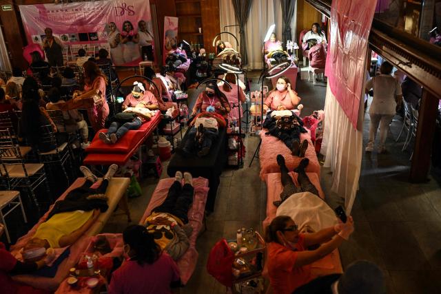 Cancer patients receive care during a free beauty and oncological micropigmentation event called "Delineating Smiles" in the Iztapalapa neighborhood of Mexico City on November 19, 2025. The "Delineating Smiles" event offered therapeutic care to women with cancer from 30 artists and professionals, including lash technicians, microblading specialists, tattoo artists and psychologists. (Photo by Yuri CORTEZ / AFP)