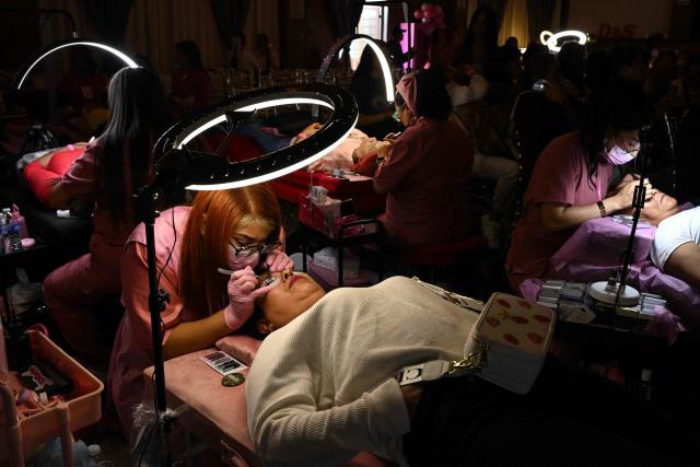 Cancer patients receive care during a free beauty and oncological micropigmentation event called "Delineating Smiles" in the Iztapalapa neighborhood of Mexico City on November 19, 2025. The "Delineating Smiles" event offered therapeutic care to women with cancer from 30 artists and professionals, including lash technicians, microblading specialists, tattoo artists and psychologists. (Photo by Yuri CORTEZ / AFP)