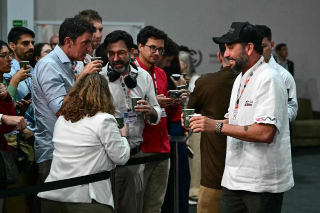 Brazilian Chef Saulo Jennings (R) hands out water to journalists during the COP30 UN Climate Change Conference in Belem, Para state, Brazil on November 19, 2025. (Photo by Pablo PORCIUNCULA / AFP)