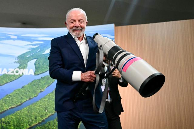Brazil's President Luiz Inacio Lula da Silva holds a camera lens before a press conference during the COP30 UN Climate Change Conference in Belem, Para state, Brazil, on November 19, 2025. Brazilian President Luiz Inacio Lula da Silva hit the corridors of COP30 in Belem on Wednesday, in a push to land a deal at the UN climate talks as nations remained divided over contentious issues. (Photo by Pablo PORCIUNCULA / AFP)