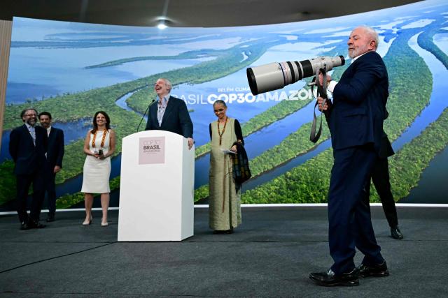 Brazil's President Luiz Inacio Lula da Silva holds a camera lens during a press conference with COP30 President Andre Correa do Lago (C, left) and Environment Minister Marina Silva (C, right) at the COP30 UN Climate Change Conference in Belem, Para state, Brazil, on November 19, 2025. Brazilian President Luiz Inacio Lula da Silva hit the corridors of COP30 in Belem on Wednesday, in a push to land a deal at the UN climate talks as nations remained divided over contentious issues. (Photo by Pablo PORCIUNCULA / AFP)