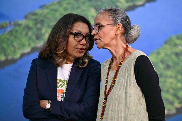Brazil's First Lady Rosangela "Janja" da Silva (L) and Environment Minister Marina Silva talk as Brazil's President Luiz Inacio Lula da Silva (out of frame) speaks during a press conference at the COP30 UN Climate Change Conference in Belem, Para state, Brazil, on November 19, 2025. Brazilian President Luiz Inacio Lula da Silva hit the corridors of COP30 in Belem on Wednesday, in a push to land a deal at the UN climate talks as nations remained divided over contentious issues. (Photo by Pablo PORCIUNCULA / AFP)