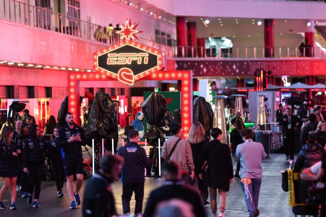 A sign for ESPN is displayed as people walk through the paddock ahead of the Las Vegas Formula One Grand Prix on November 19, 2025, in Las Vegas, Nevada. (Photo by Patrick T. Fallon / AFP)