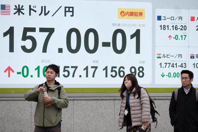 Pedestrians stand in front of an electronic quotation boards displaying the foreign exchange rate of the US dollar against the Japanese yen during a morning session in Tokyo on November 20, 2025. (Photo by Kazuhiro NOGI / AFP)