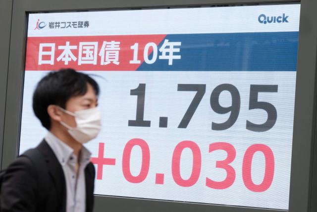 A man walks past an electronic quotation board displaying the long-term interest rates on the Tokyo bond market in Tokyo on November 20, 2025. (Photo by Kazuhiro NOGI / AFP)
