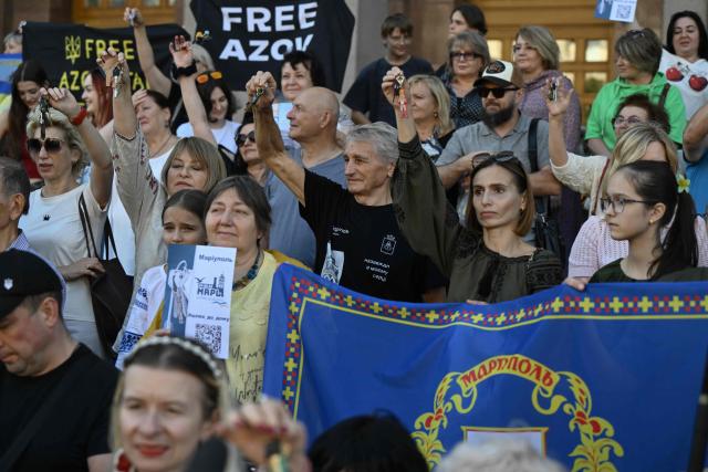 (FILES) Former residents of Mariupol, who were forced to leave their homes due to the Russian invasion hold keys of their abandoned flats during a meeting in central Kyiv on September 21, 2025, to mark the Day of the city of Mariupol, amid the Russian invasion of Ukraine. The Russian security agents were smirking. David was panicking. As the hours-long interrogation dragged on, he worried they would send him back to occupied Mariupol, and into the ranks of Russia's army. (Photo by Genya SAVILOV / AFP)