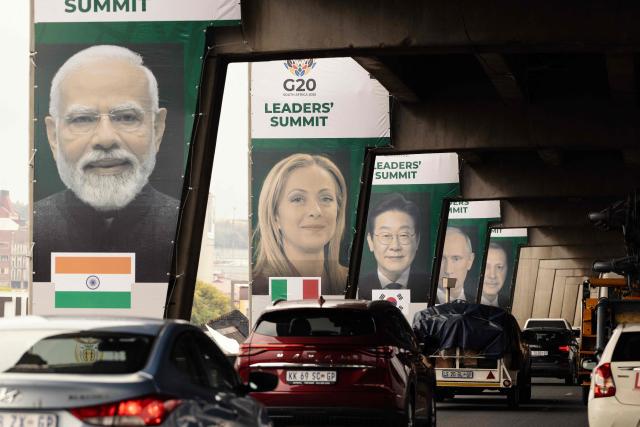 Banners of (from L to R) India's Prime Minister Narendra Modi, Italy's Prime Minister Giorgia Meloni and South Korea's President Lee Jae Myung are displayed on pillars of an highway overpass in Johannesburg on November 20, 2025. (Photo by GIANLUIGI GUERCIA / AFP)