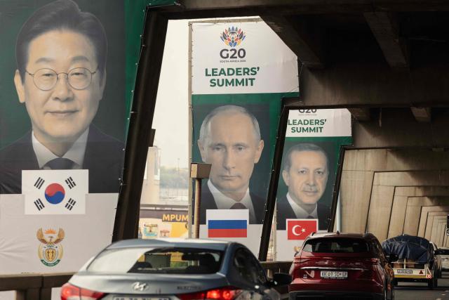 Banners of (from L to R) South Korea's President Lee Jae Myung, Russia's President Vladimir Putin and Turkey's President Recep Tayyip Erdogan are displayed on pillars of an highway overpass in Johannesburg on November 20, 2025 ahead of the G20 leader's Summit. (Photo by GIANLUIGI GUERCIA / AFP)