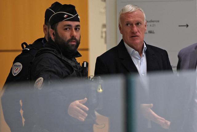 France's football team head coach Didier Deschamps (R) speaks with a police officer as he arrives at the Criminal Court for the slander lawsuit against French Sports journalist Daniel Riolo in Paris on November 20, 2025. Riolo is facing trial on November 20, 2025 for slander after accusing France's national football team headcoach Didier Deschamps of "lying" about the severity of France's forward Karime Benzema's injury during the 2022 World Cup in Qatar. (Photo by Anne-Christine POUJOULAT / AFP)