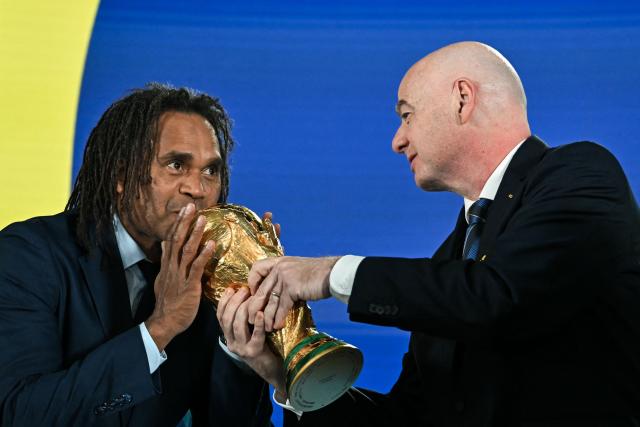 French former player Christian Karembeu kisses the 2026 FIFA World Cup trophy FIFA handed by President Gianni Infantino following the 2026 FIFA World Cup European Play-Off draw at the FIFA's Home of Football in Zurich on November 20, 2025. (Photo by Fabrice COFFRINI / AFP)