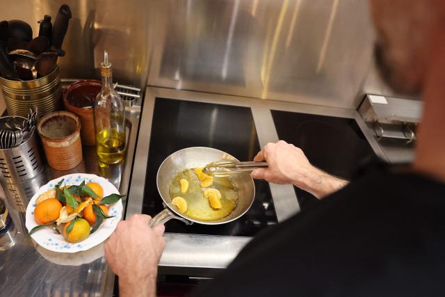 Chef Romain Rontodi of the Rosette et Charlot restaurant cooks Corsican clementines to prepare a dessert at the restaurant in Ajaccio, on the French Mediterranean island of Corsica, on November 15, 2025. (Photo by Pascal POCHARD-CASABIANCA / AFP)