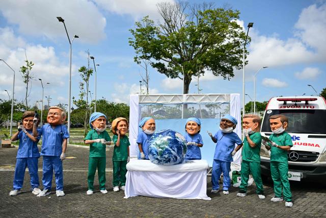 Oxfam activists wearing oversized masks representing (L to R) Argentina's President Javier Milei, US President Donald Trump, Canada's Prime Minister Mark Carney, European Commission President Ursula Von der Leyen, Brazil's President Luiz Inacio Lula da Silva, Mexico's President Claudia Sheinbaum, South Africa's President Cyril Ramaphosa, Britain's Prime Minister Keir Starmer and France's President Emmanuel Macron pose during their "Big Heads" protest at Utinga Park in Belem, Para, on November 20, 2025, to simulate a chaotic emergency room and highlight that as COP30 ends, the planet is in critical condition. With UN climate talks nearing a close in Belem, the world body's chief on Thursday urged nations to reach an "ambitious compromise" that keeps alive the goal of limiting long-term planetary warming to the critical 1.5C threshold. (Photo by Pablo PORCIUNCULA / AFP)