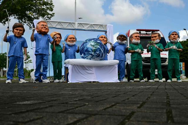 Oxfam activists wearing oversized masks representing (L to R) Argentina's President Javier Milei, US President Donald Trump, European Commission President Ursula Von der Leyen, Brazil's President Luiz Inacio Lula da Silva, Mexico's President Claudia Sheinbaum, South Africa's President Cyril Ramaphosa, Britain's Prime Minister Keir Starmer, France's President Emmanuel Macron and Canada's Prime Minister Mark Carney pose during their "Big Heads" protest at Utinga Park in Belem, Para, on November 20, 2025, to simulate a chaotic emergency room and highlight that as COP30 ends, the planet is in critical condition. Brazilian President Luiz Inacio Lula da Silva put his "roadmap" from fossil fuels back at the top of UN climate talks in Belem on Wednesday, despite the failure of a bold bid to seal an early deal. (Photo by Pablo PORCIUNCULA / AFP)