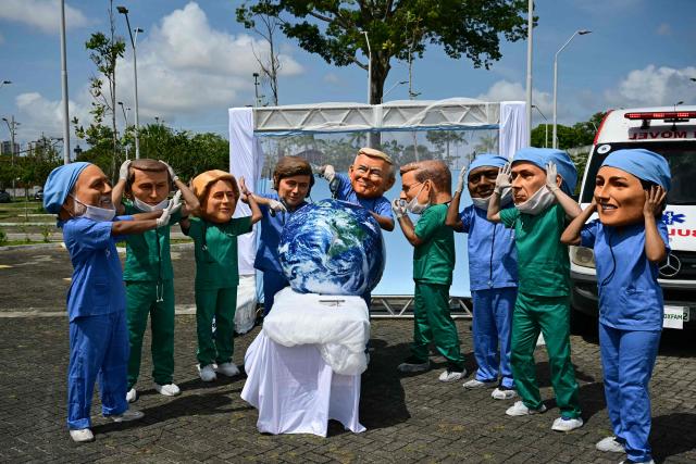 Oxfam activists wearing oversized masks representing (L to R) Brazil's President Luiz Inacio Lula da Silva, France's President Emmanuel Macron, European Commission President Ursula Von der Leyen, Argentina's President Javier Milei, US President Donald Trump, Britain's Prime Minister Keir Starmer, South Africa's President Cyril Ramaphosa, Canada's Prime Minister Mark Carney, and Mexico's President Claudia Sheinbaum, pose during their "Big Heads" protest at Utinga Park in Belem, Para, on November 20, 2025, to simulate a chaotic emergency room and highlight that as COP30 ends, the planet is in critical condition. With UN climate talks nearing a close in Belem, the world body's chief on Thursday urged nations to reach an "ambitious compromise" that keeps alive the goal of limiting long-term planetary warming to the critical 1.5C threshold. (Photo by Pablo PORCIUNCULA / AFP)